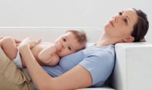 Trött mamma med bebis