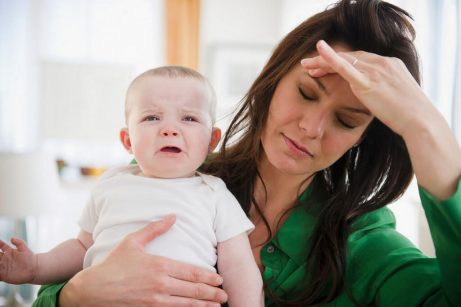 Ledsen bebis med trött mamma