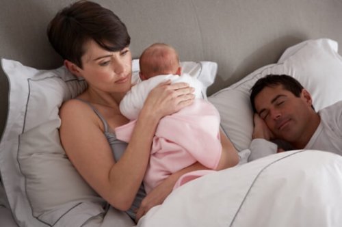 Mor som håller baby i säng