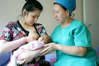 Mor som ammar bebis med sköterska