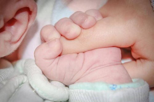 Bebis som håller i finger.