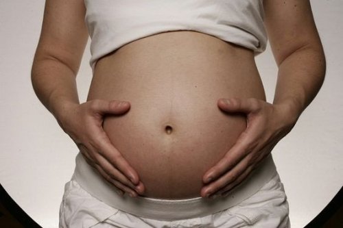 Gravid kvinna som håller sin mage.