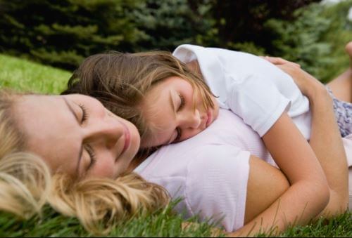 Mor och dotter som ligger på gräset.