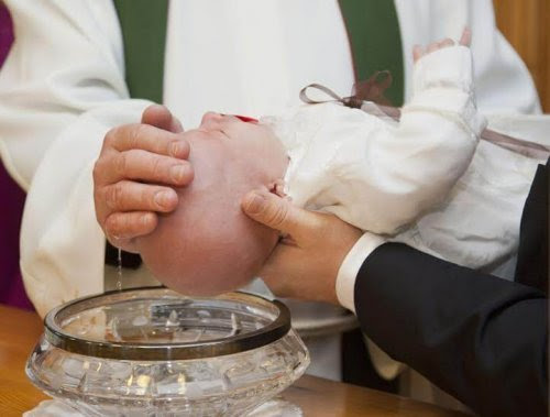 Gudförälder håller fram spädbarn som blir döpt av präst