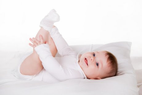 Bebis på skötbord leker med sina fötter