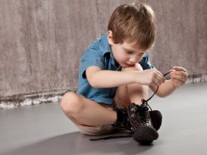 Pojke som lär sig att knyta skorna