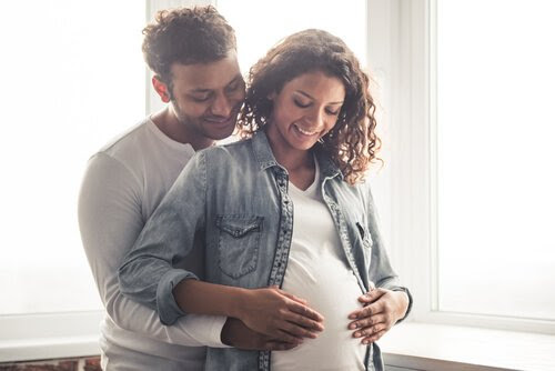 Man och gravid kvinna känner på magen