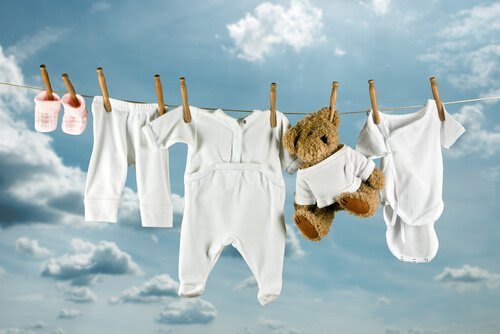 Barnkläder och en nalle hänger på tvättlina
