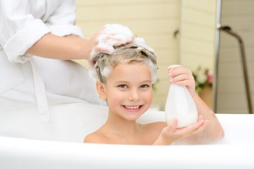barn i badkar med schampoo i håret