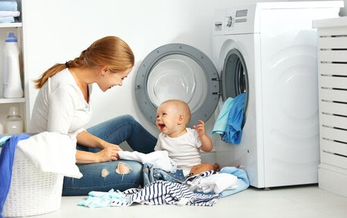 mamma och bebis sorterar tvätt vid tvättmaskin