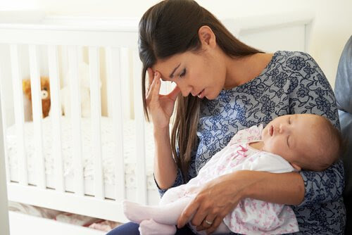ledsen mamma med sovande spädbarn i famnen