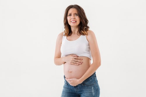 9 sätt din kropp förändras under graviditeten: kvinna ser orolig ut och håller sig om sin gravida mage