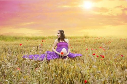 Gravid kvinna i ett soligt fält med blommor
