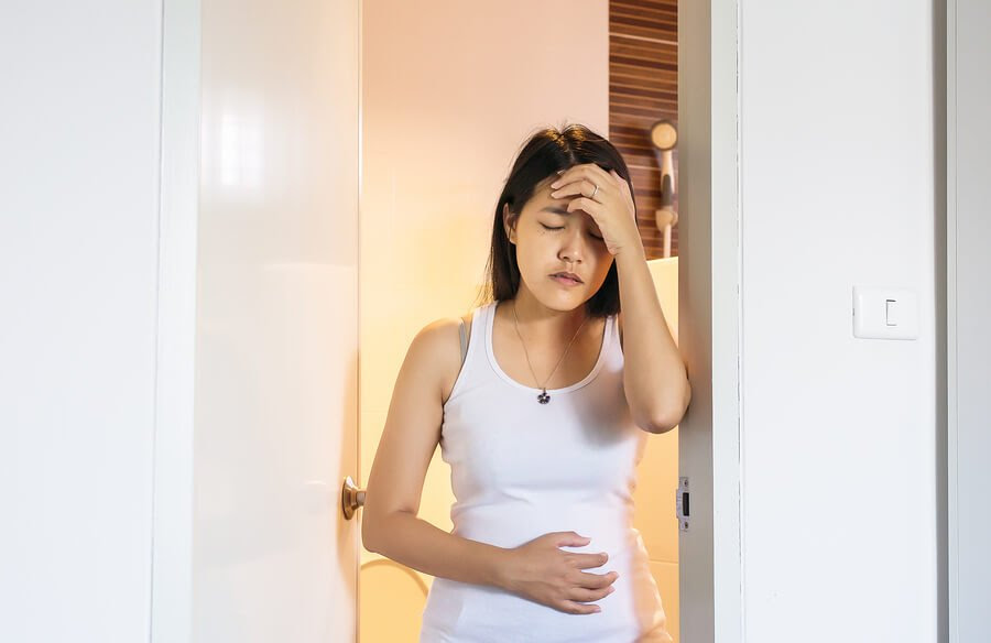 Kroppen förändras under graviditeten: Kvinna håller sig för magen och pannan