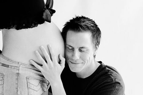 Fader kramar gravid kvinnas mage
