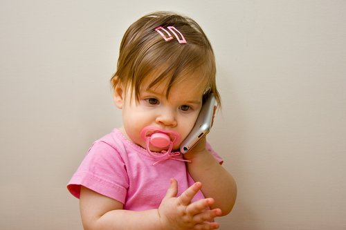 Ett litet barn leker att hon pratar i telefon.