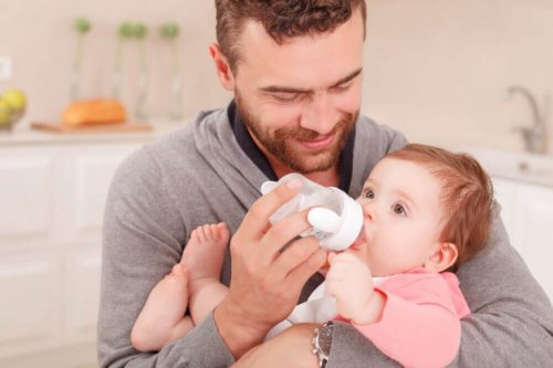 En pappa matar sin bebis med nappflaska.