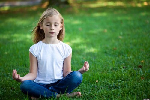En flicka mediterar i en park.