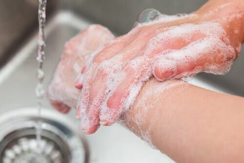 handtvätt: händer med tvållödder nära vattenstråle