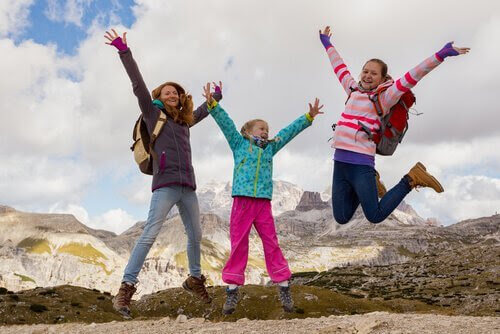 Tre flickor hoppar mot bakgrund av berg