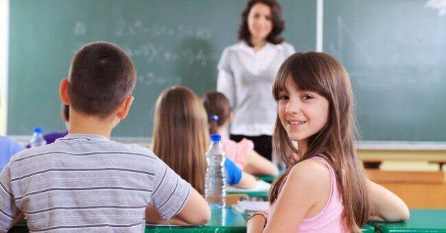 Flicka tittar in i kameran i klassrum