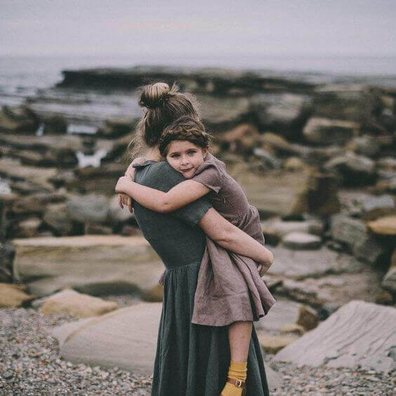 Mamma håller dotter på strand