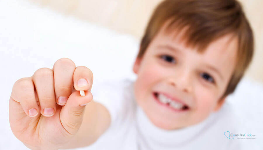Pojke ler och visar en tand i handen