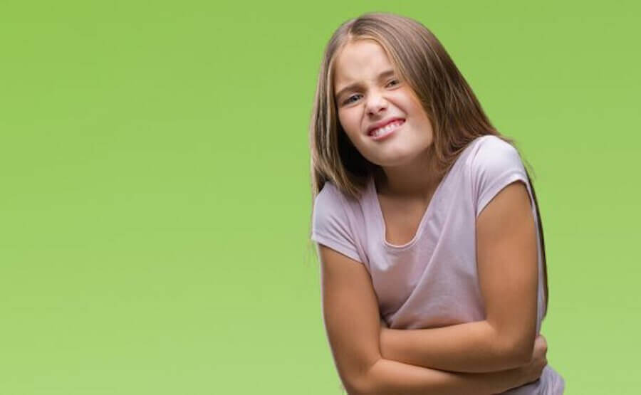 flicka grimaserar och håller sig om magen