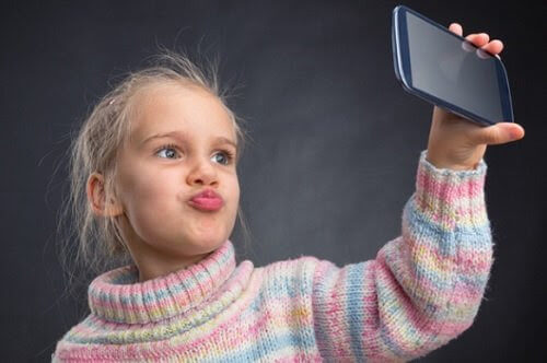 barn håller mobiltelefon tar selfie