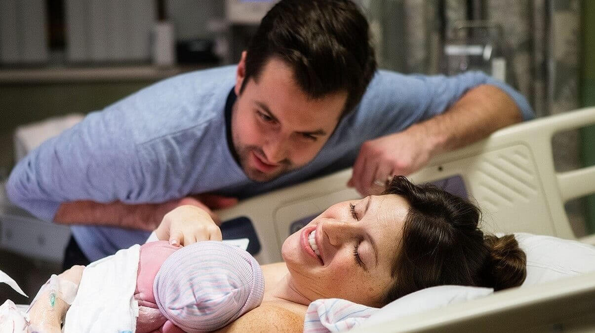 Inducera förlossningen: Mamma och pappa tittar på nyfödd