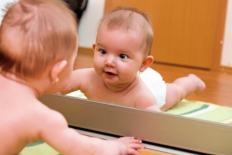 Bebis som tittar förvånat i spegeln.