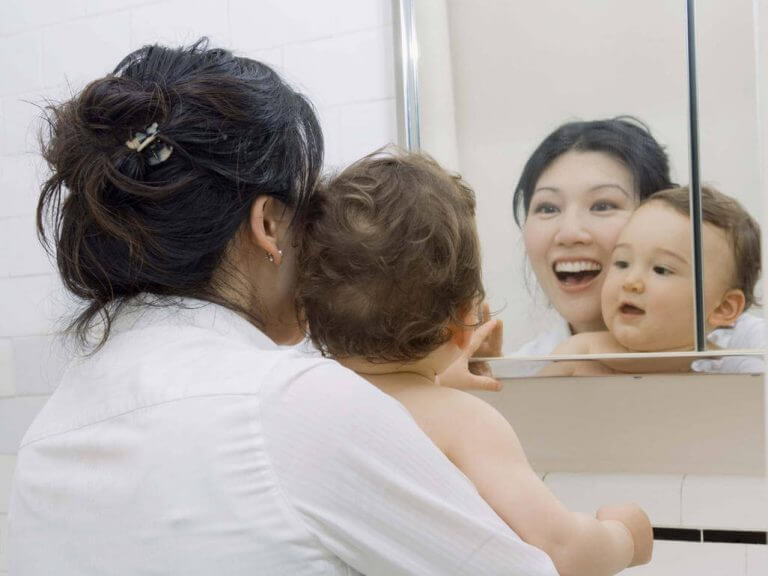 Mamma med bebis framför spegeln.