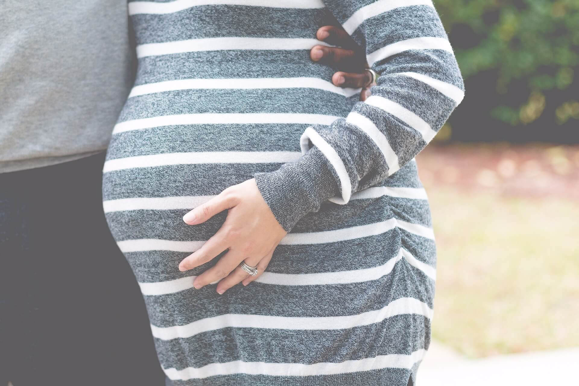 gravid kvinna håller sig om magen, man står bredvid henne