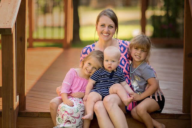 Mamma sitter med tre barn på trappa