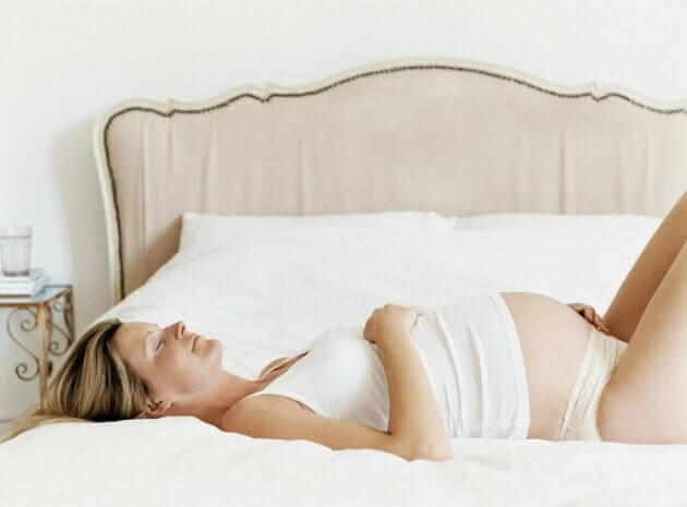 gravid kvinna slappnar av på säng