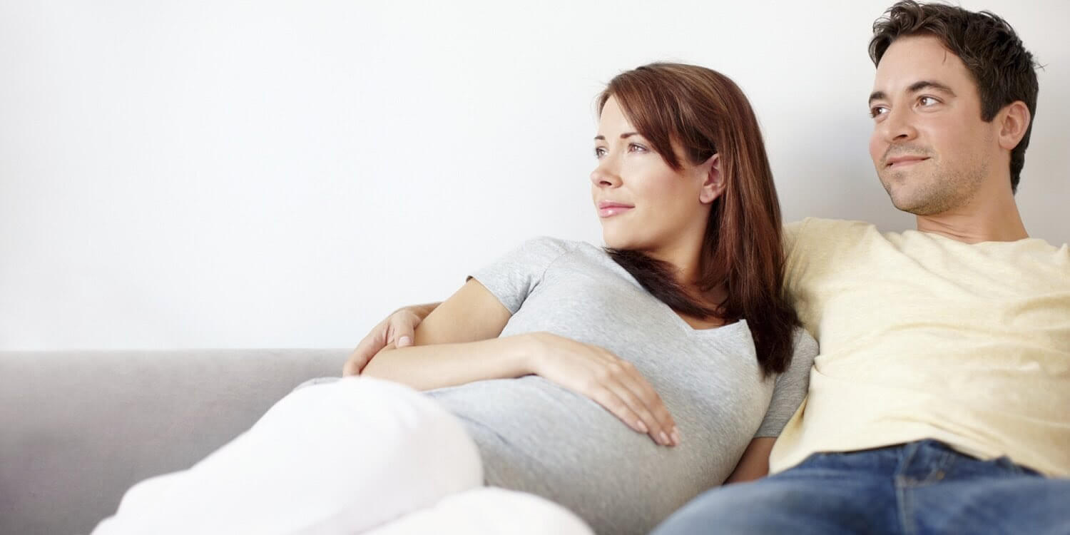 man och gravid kvinna i soffa