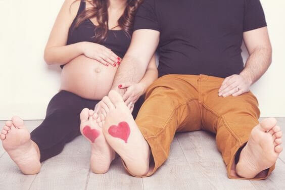 gravid kvinna och man med hjärtan målade på fotsulorna