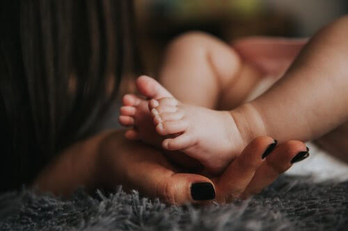 hand håller fötter på nyfödd