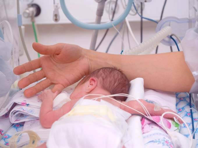 vuxen hand håller för tidigt fött barns hand
