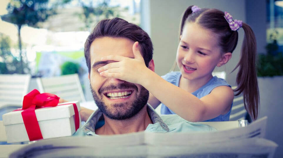 flicka ger pappa present och håller för ögonen på honom