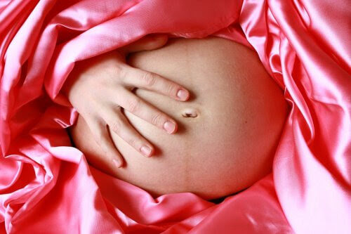 gravid mage insvept i rosa silke