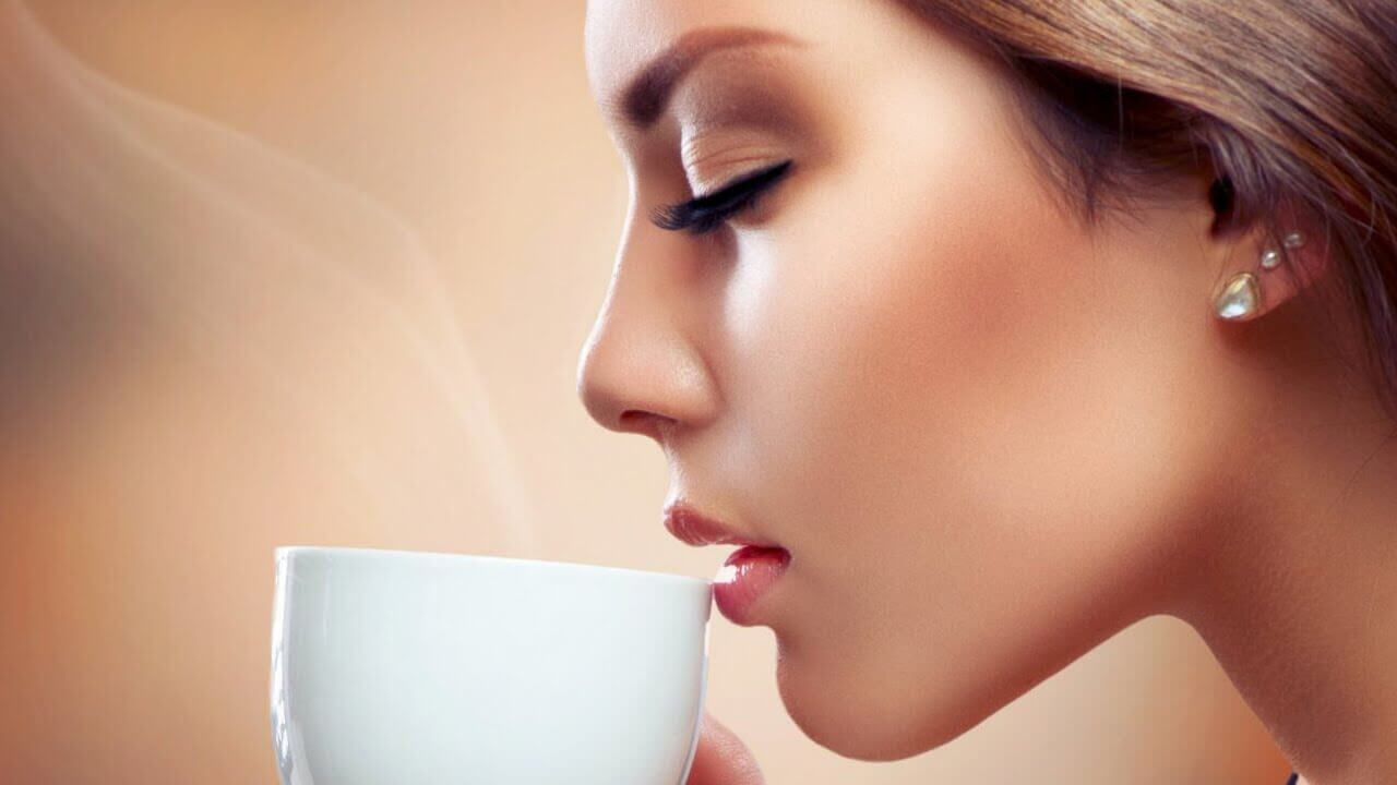 kvinna dricker en kopp kaffe med slutna ögon