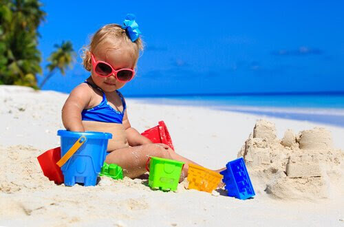 baby på stranden med sandleksaker