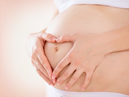 gravid kvinna håller händerna framför magen som ett hjärta