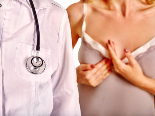 Mastit: kvinna håller sig för bröstet, läkare i förgrunden