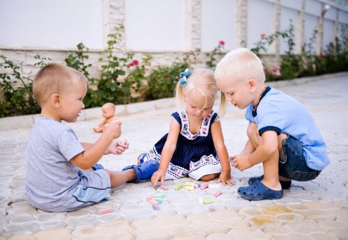 tre barn leker med kritor