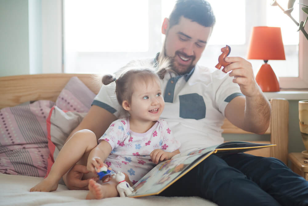 pappa tittar i bok och leker med dotter