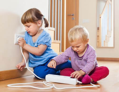 liten flicka och pojke leker med eluttag
