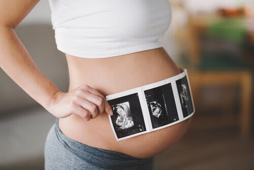 gravid kvinna hålla ultraljudsbilder framför magen