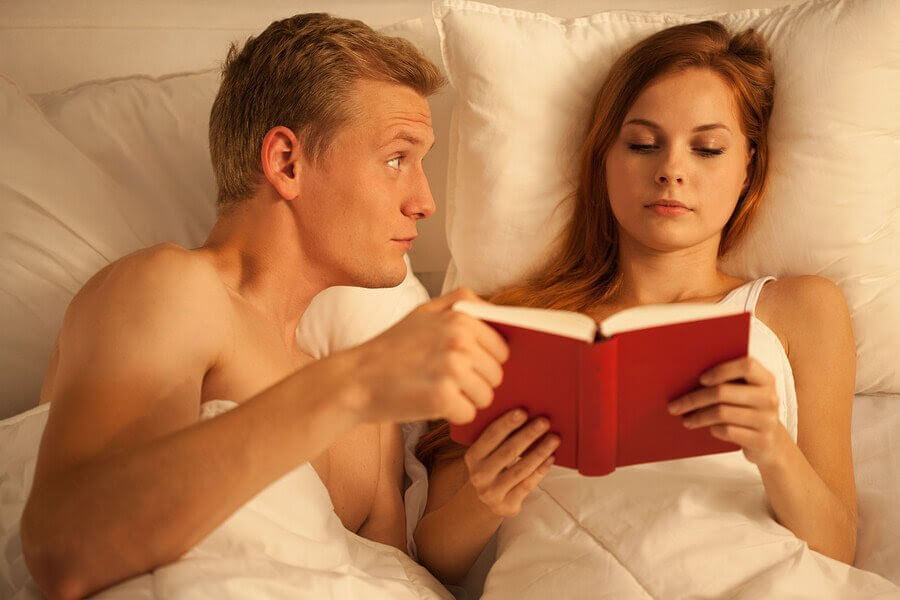sexualitet och amning: man och kvinna i säng, kvinnan läser och mannen håller en hand på hennes bok
